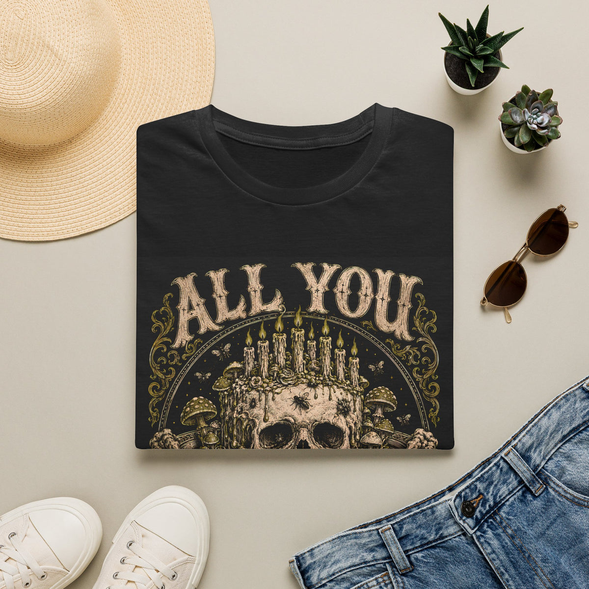 Folded black t-shirt with All You Can Rot text and skull crowned with candles, styled flat lay.